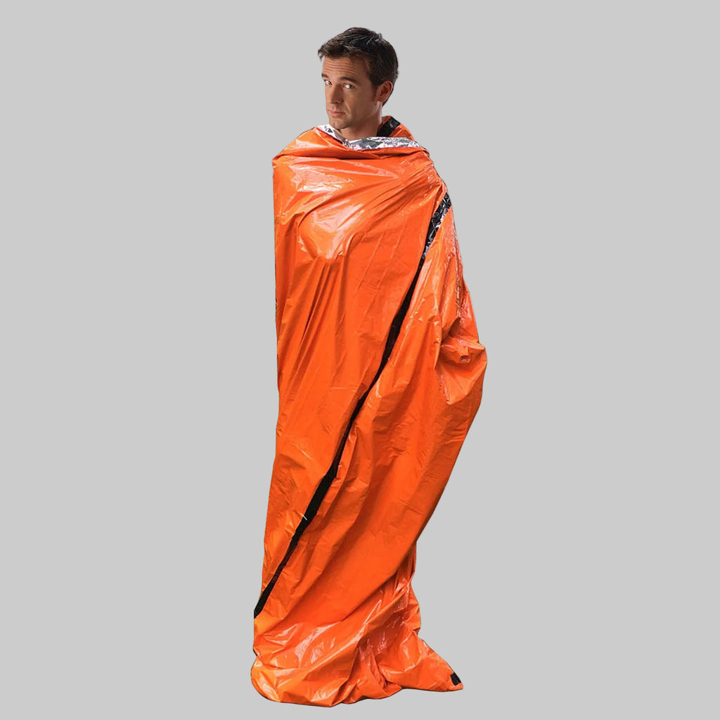 Person wrapped in an orange emergency blanket on a white background